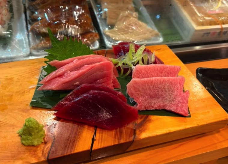 A board of lean, medium and fatty tuna cuts served beside marbled beef