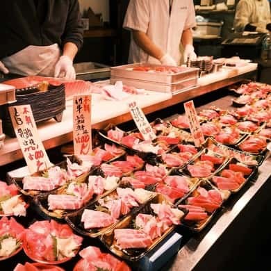 Cut tuna laid out with handwritten price tags on a market counter