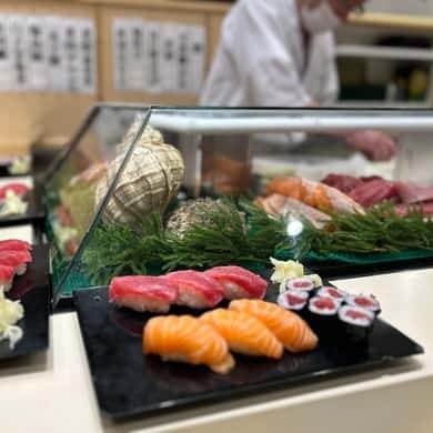 A plate of market sushi served on slate at a counter inside the market