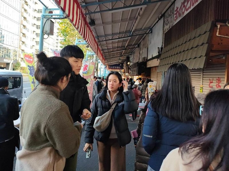 Shoppers moving between stalls in the narrow lanes of the Tsukiji Outer Market